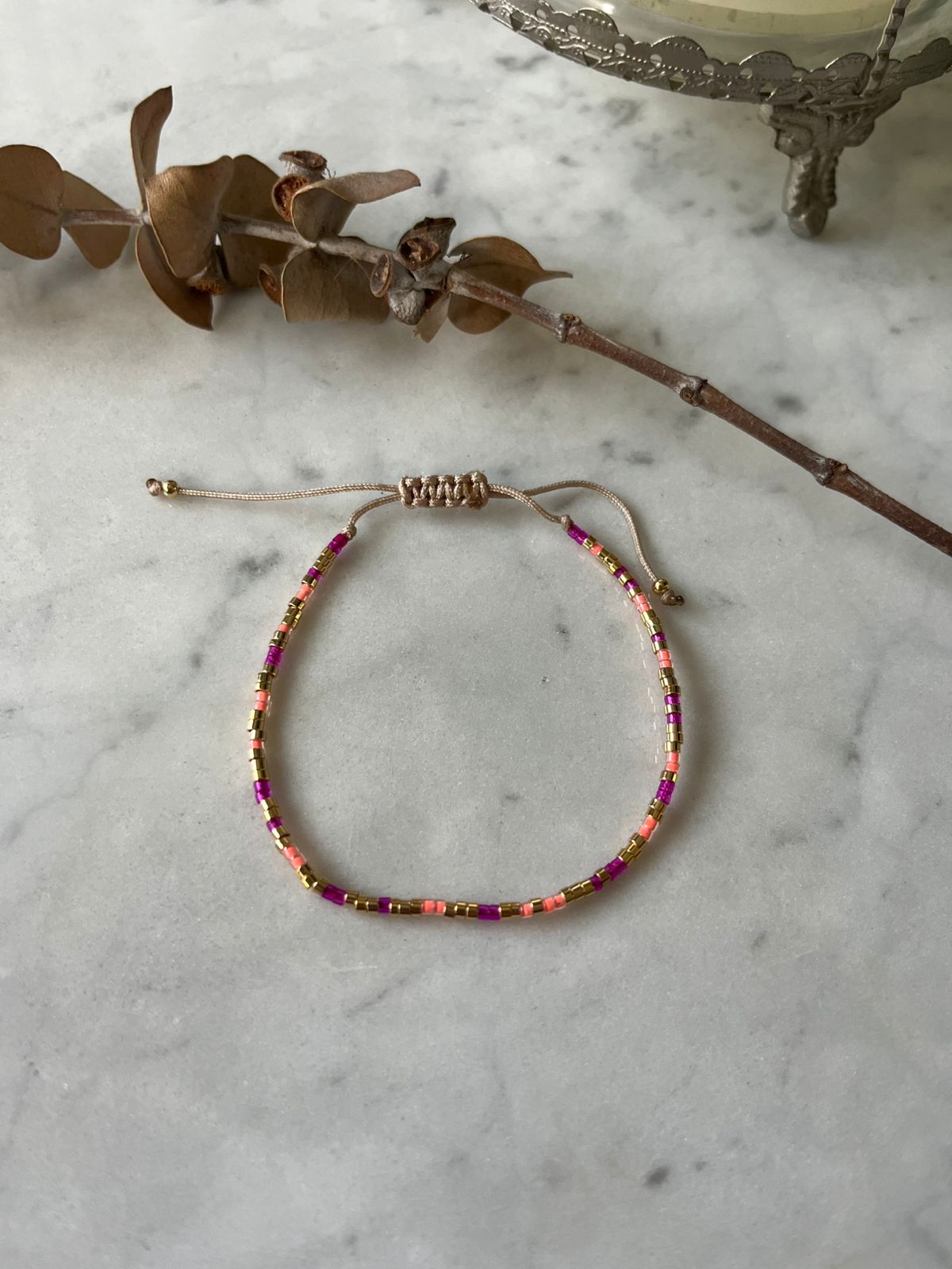 Pulsera de hilo con detalles en fucsia y mostacillas en baño de oro de 24 k