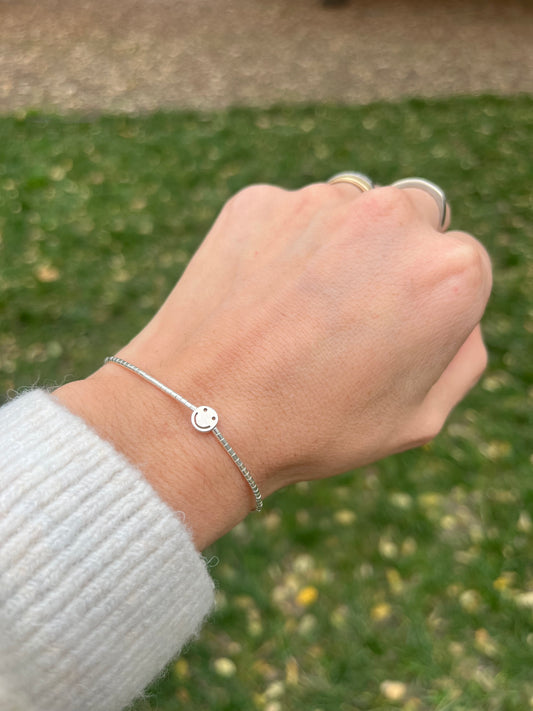 Pulsera hilo gris con mostacillas y Smile de plata