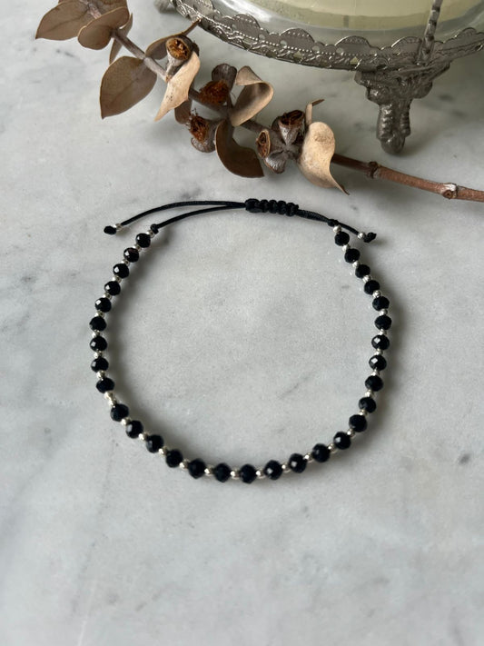 Pulsera de hilo negro con cristales negros y mostacillas de plata