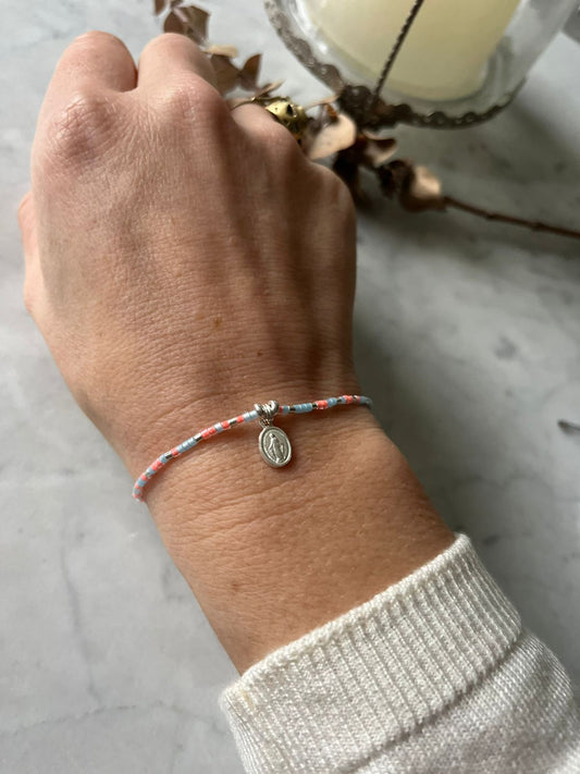 Pulsera de hilo cristales celeste rosados, con virgen de los rayos y detalles de plata, ajustable de 15cm a 20cm