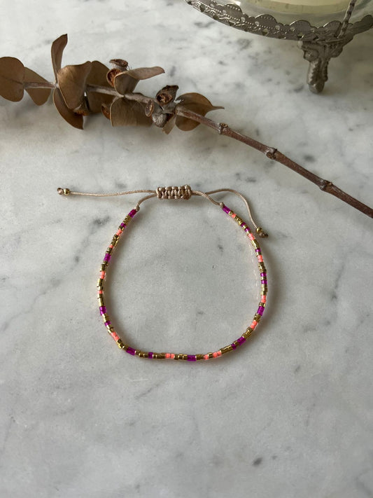 Pulsera de hilo con detalles en fucsia y mostacillas en baño de oro de 24 k